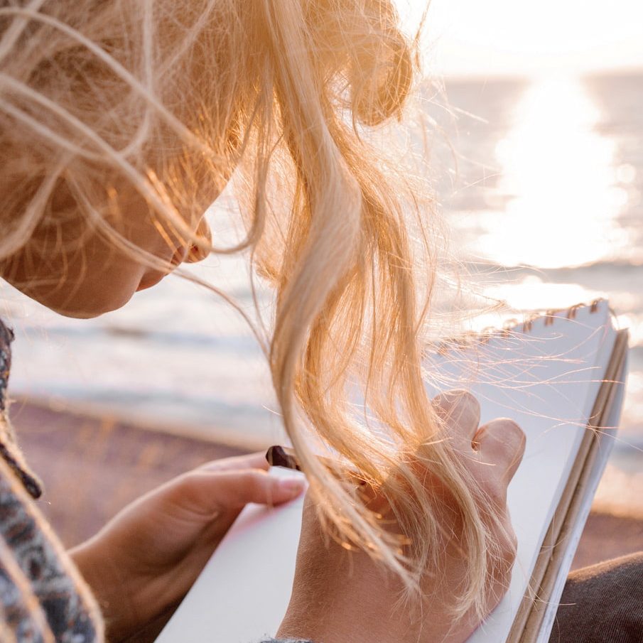 Frau schreibt am Strand im Sonnenlicht